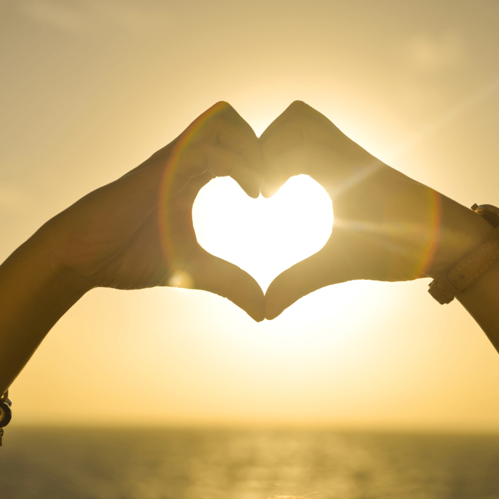 A hand shaped in a heart surround the sun